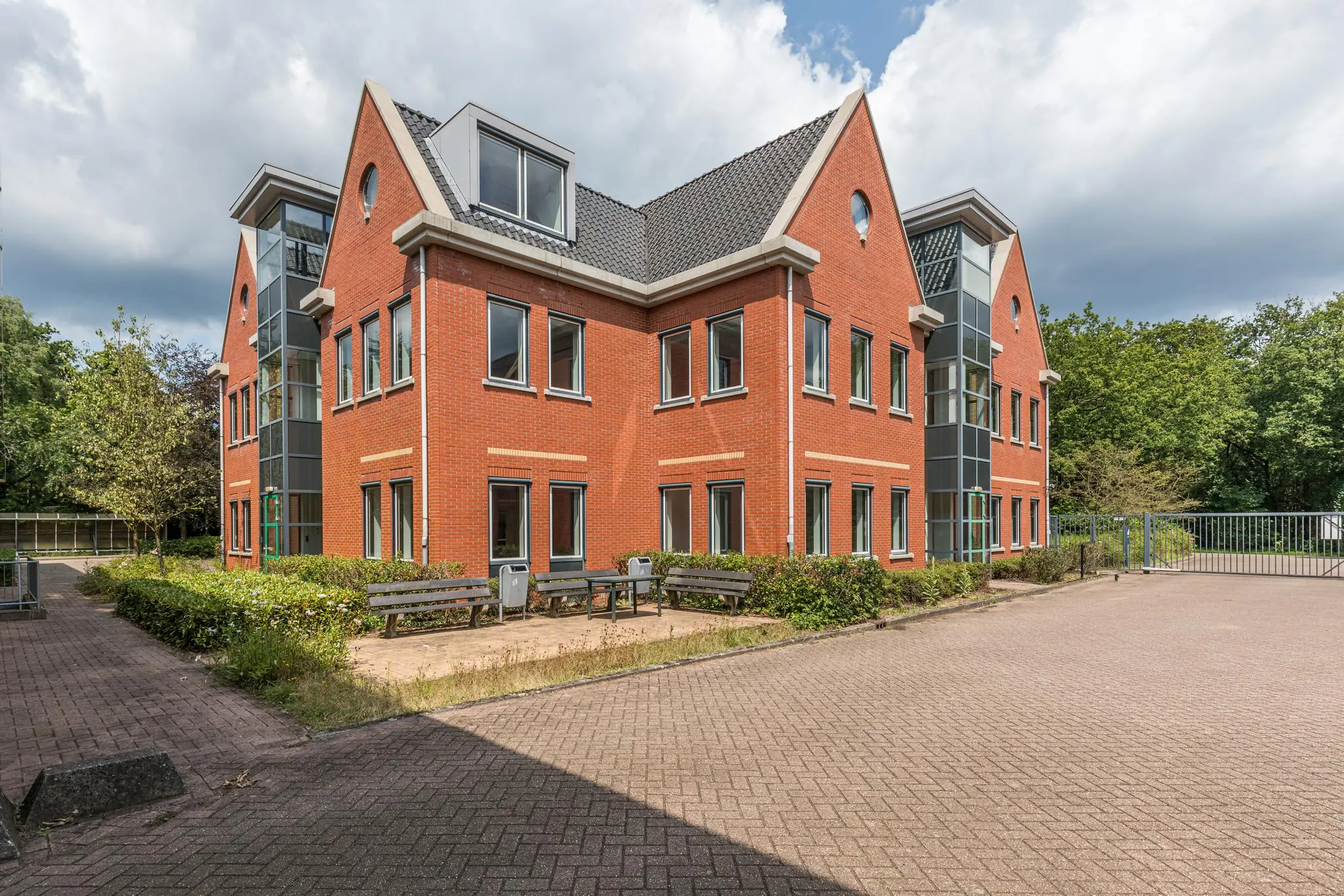 Modern rood bakstenen kantoorpand aan de Laan Blussé van Oud-Alblas met grote ramen en een betegeld buitenterrein.